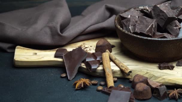 Piezas de chocolate orgánico oscuro o lácteo y caramelos de trufa en un tazón de madera sobre fondo de hormigón oscuro — Vídeo de stock