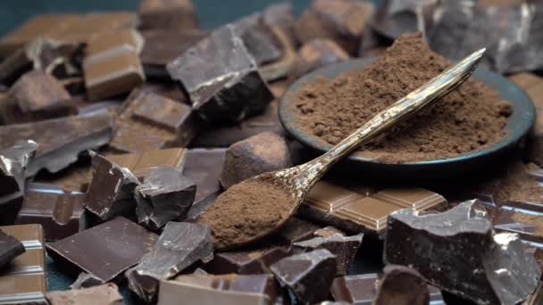 Donkere of melk biologische chocolade stukjes, cacaopoeder en truffel snoepjes op donkere betonnen achtergrond — Stockvideo