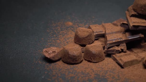 Pedaços de chocolate orgânico escuro ou de leite, cacau em pó e doces de trufa em fundo de concreto escuro — Vídeo de Stock