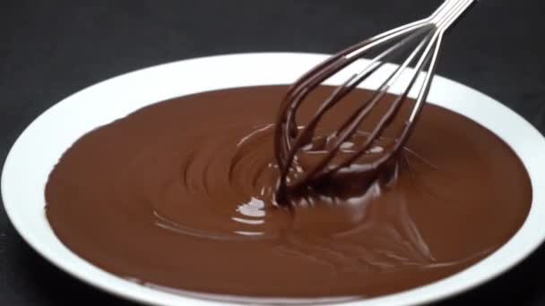 녹은 우유 또는 진한 초콜렛의 매크로가 접시에 소용돌이 치고 콘크리트 배경에 휘 젓 습니다. — 비디오