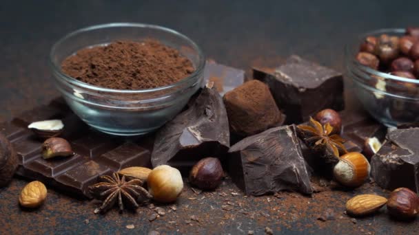 Montón de trozos de chocolate rotos y nueces sobre fondo de hormigón oscuro — Vídeo de stock