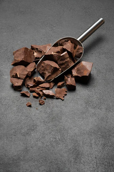Morceaux de chocolat noir en cuillère métallique sur fond de béton foncé — Photo