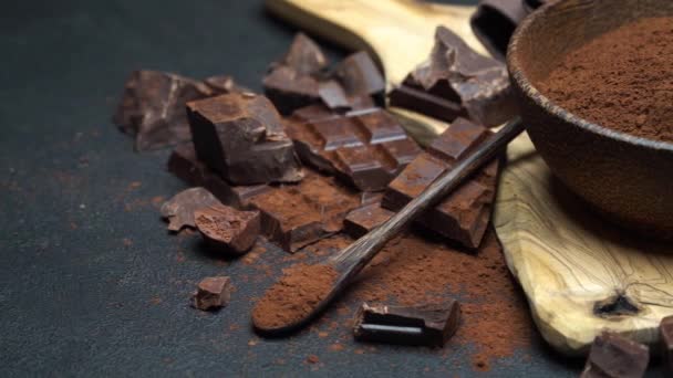 Cioccolato fondente e cacao in polvere in ciotola di legno su fondo di cemento scuro — Video Stock