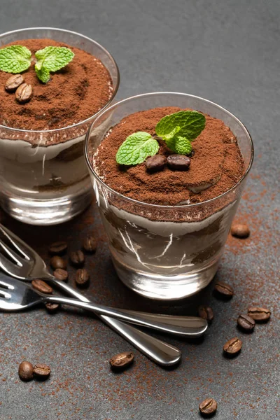 Due porzioni Classico dessert tiramisù in un bicchiere su sfondo di cemento scuro — Foto Stock
