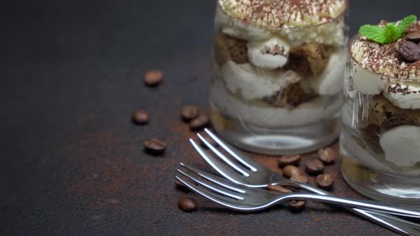 Dua porsi makanan penutup tiramisu klasik dalam gelas dengan latar belakang beton gelap — Stok Video