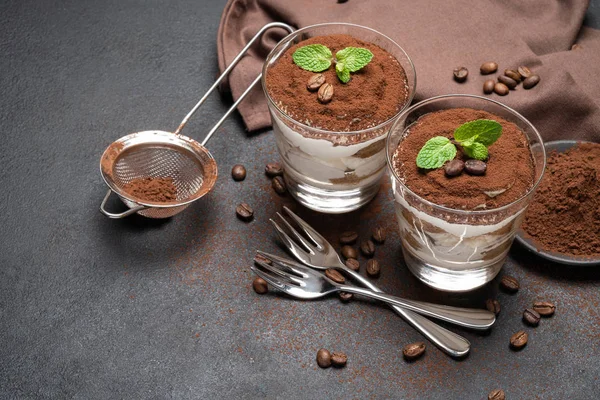 Zwei Portionen klassisches Tiramisu-Dessert im Glas auf dunklem Betongrund — Stockfoto
