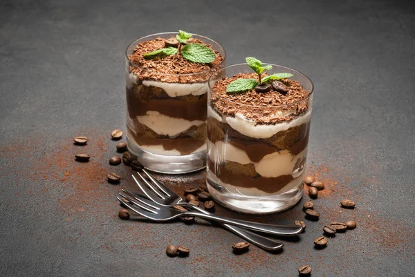 Zwei Portionen klassisches Tiramisu-Dessert im Glas auf dunklem Betongrund — Stockfoto