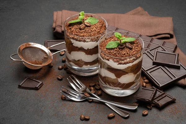 Duas porções Sobremesa tiramisu clássica em uma barra de vidro e chocolate no fundo de concreto escuro — Fotografia de Stock