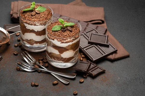 Zwei Portionen klassisches Tiramisu-Dessert in Glas und Schokoriegel auf dunklem Betongrund — Stockfoto