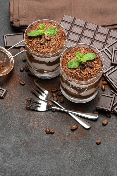 Duas porções Sobremesa tiramisu clássica em uma barra de vidro e chocolate no fundo de concreto escuro — Fotografia de Stock