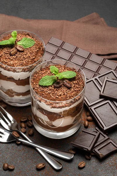 Zwei Portionen klassisches Tiramisu-Dessert in Glas und Schokoriegel auf dunklem Betongrund — Stockfoto