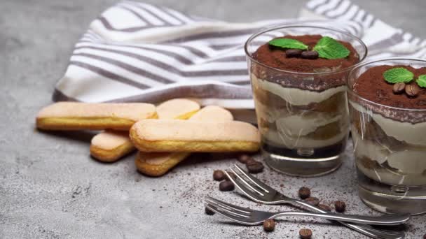 Två portioner klassisk tiramisu dessert i ett glas och kopp kaffe på betong bakgrund — Stockvideo