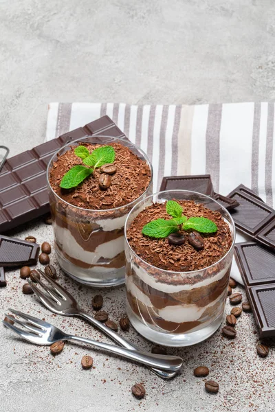 Zwei Portionen klassisches Tiramisu-Dessert in Glas und Schokoriegel auf Betongrund — Stockfoto