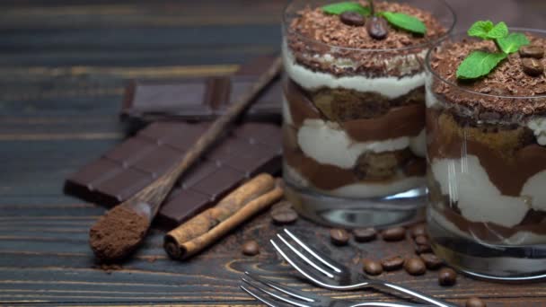 Två portioner klassisk tiramisu dessert i en glas-och chokladkaka på trä bakgrund — Stockvideo