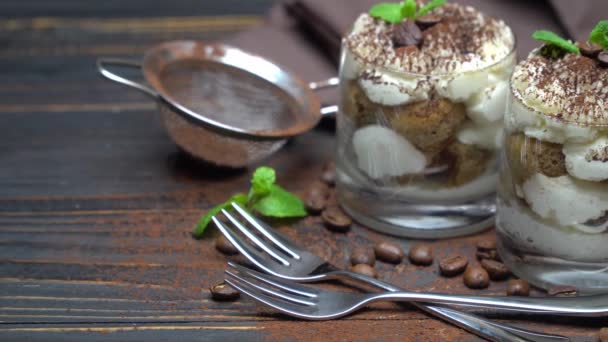 Two portions Classic tiramisu dessert in a glass on wooden background — Stock Video