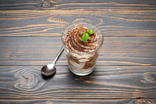 Porzione di dolce tiramisù classico in un bicchiere su fondo di legno — Foto Stock