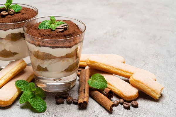 Sobremesa tiramisu clássica em um copo e biscoitos savoiardi no fundo de concreto — Fotografia de Stock