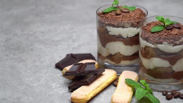 Классический десерт тирамису в стакане и печенье савойарди на бетонном фоне — стоковое видео