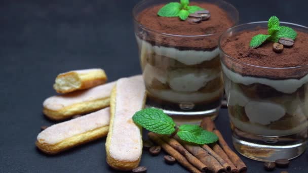 Klassisches Tiramisu-Dessert im Glas und savoiardi-Kekse auf dunklem Betongrund — Stockvideo