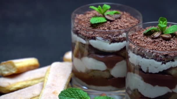 Classic tiramisu dessert in a glass and savoiardi cookies on dark concrete background — Stock Video