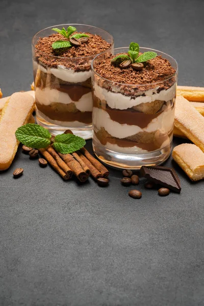 Sobremesa tiramisu clássica em um copo e biscoitos savoiardi no fundo de concreto escuro — Fotografia de Stock