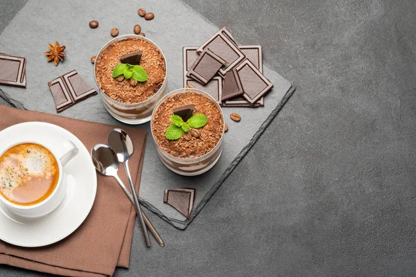 Классический десерт тирамису в стакане и чашка кофе на темном бетонном фоне — стоковое фото
