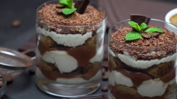 Postre tiramisú clásico en un vaso y una taza de café sobre fondo de hormigón oscuro — Vídeos de Stock