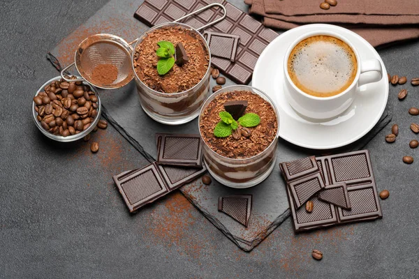 Классический десерт тирамису в стакане и чашка кофе на темном бетонном фоне — стоковое фото