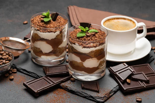 Klasyczne tiramisu deser w szklance i filiżankę kawy na ciemnym tle betonu — Zdjęcie stockowe