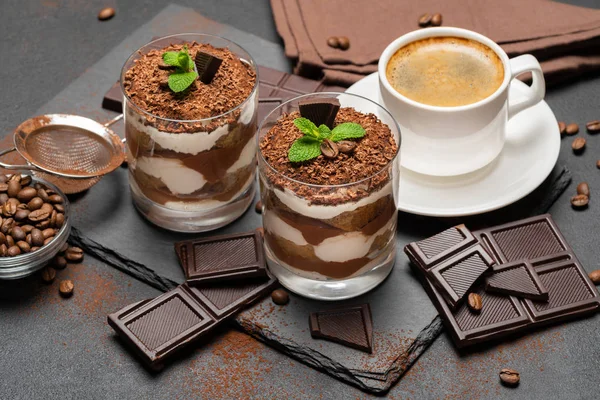 Klassisches Tiramisu-Dessert in Glas und Tasse Kaffee auf dunklem Betongrund — Stockfoto