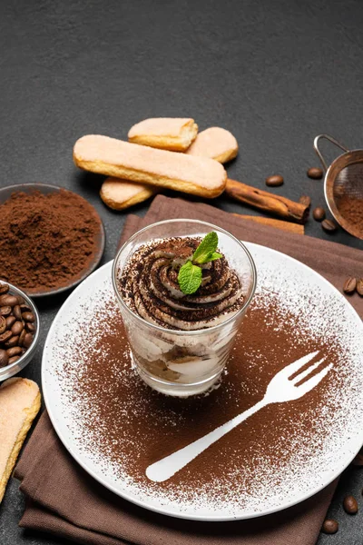 Dessert tiramisu classique dans un verre et une tasse de café sur fond de béton foncé — Photo