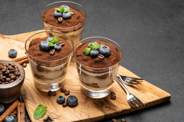 Postre tiramisú clásico en una copa con arándanos sobre fondo de hormigón oscuro —  Fotos de Stock