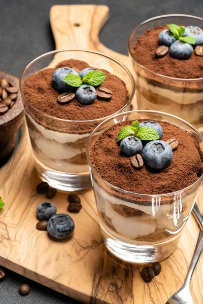 Klassisches Tiramisu-Dessert im Glas mit Blaubeeren auf dunklem Betongrund — Stockfoto