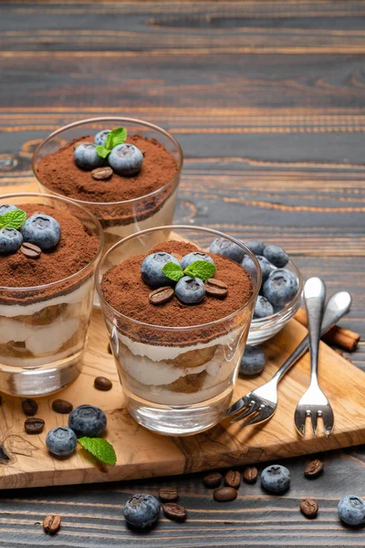 Classic tiramisu dessert in a glass with blueberries on wooden background — Stock Photo, Image