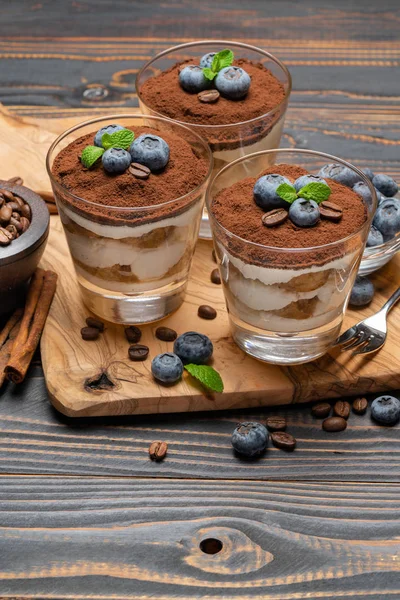 Klassisches Tiramisu-Dessert im Glas mit Blaubeeren auf Holzgrund — Stockfoto