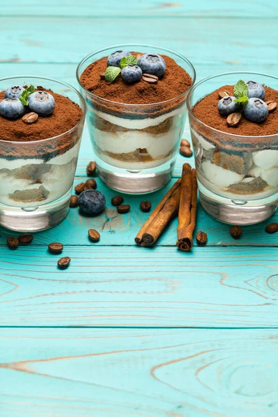 Sobremesa tiramisu clássica em um copo com mirtilos em fundo de madeira azul — Fotografia de Stock