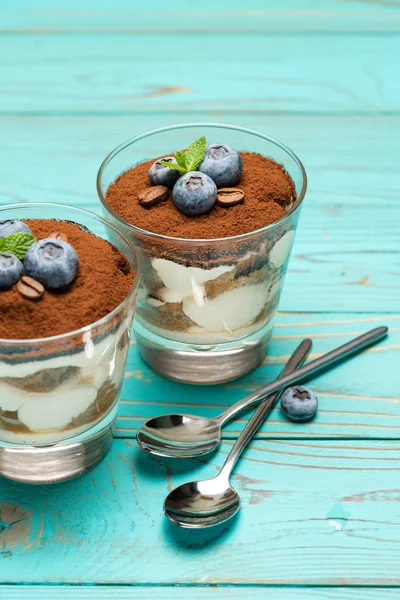 Classic tiramisu dessert in a glass with blueberries on blue wooden background — Stock Photo, Image