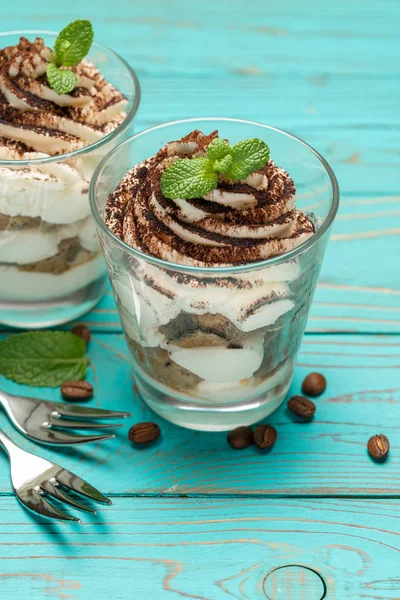 Sobremesa tiramisu clássico em um copo em fundo de madeira azul — Fotografia de Stock