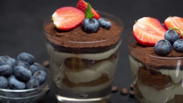 经典的提拉米苏甜点，在深色混凝土背景的玻璃杯中提供蓝莓和草莓 — 图库视频影像
