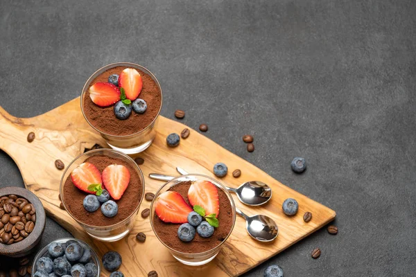 Klasszikus tiramisu desszert áfonyával és eper egy pohár sötét beton háttér — Stock Fotó