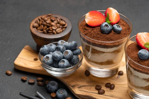 Klassiek Tiramisu-dessert met bosbessen en aardbeien in een glas op een donkere betonnen achtergrond — Stockfoto