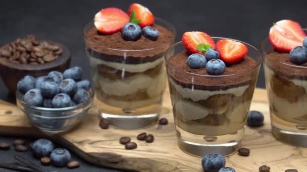 经典的提拉米苏甜点，在深色混凝土背景的玻璃杯中提供蓝莓和草莓 — 图库视频影像