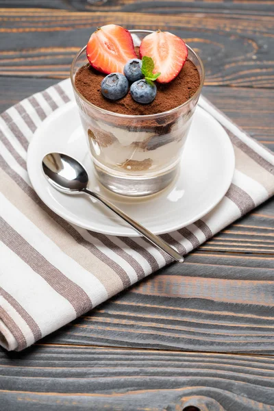 Klassisk tiramisu dessert med blåbär och jordgubbar i ett glas på trä bakgrund — Stockfoto