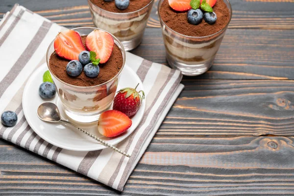 Klassiek Tiramisu-dessert met bosbessen en aardbeien in een glas op houten achtergrond — Stockfoto