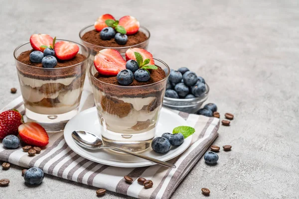 Klassiek Tiramisu-dessert met bosbessen en aardbeien in een glas op concrete achtergrond — Stockfoto