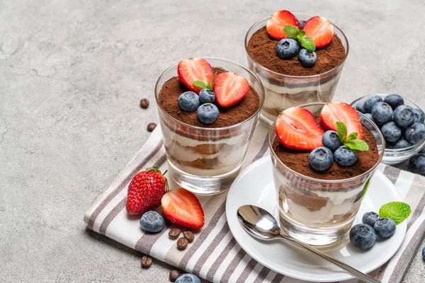 Классический десерт с черникой и клубникой в стакане на бетонном фоне — стоковое фото
