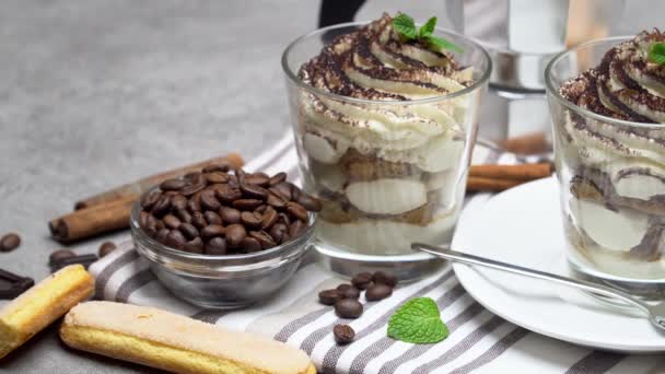 Postre tiramisú clásico en vaso y cafetera sobre fondo de hormigón — Vídeos de Stock