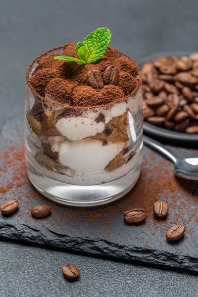 Postre tiramisú clásico en un vaso sobre tabla de servir de piedra sobre fondo de hormigón oscuro —  Fotos de Stock