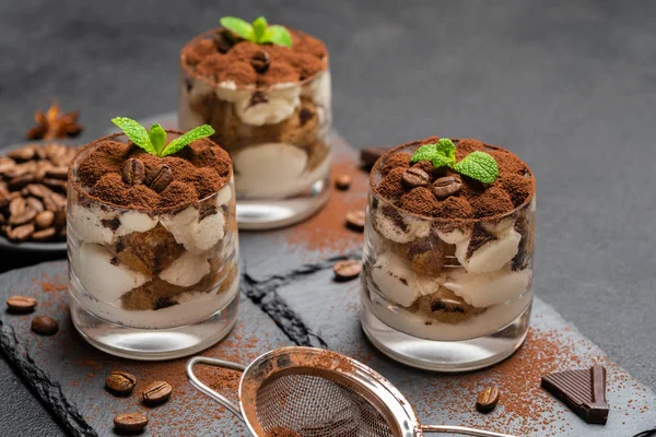 Postre tiramisú clásico en un vaso sobre tabla de servir de piedra sobre fondo de hormigón oscuro —  Fotos de Stock