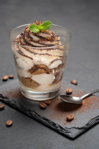 Classico dessert tiramisù in un bicchiere su tavola da portata in pietra su sfondo di cemento scuro — Foto Stock